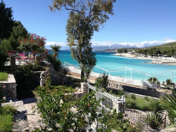 A coastal view with a stone pathway leading to a white fence overlooking turquoise waters. - EMAR Beachfront Hotel Ksamil (Ksamil)