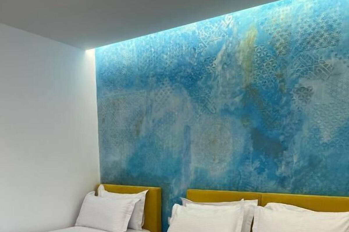 A hotel room with two beds, each with white bedding and yellow headboards.
