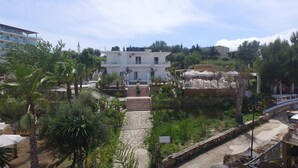 A hotel with a central staircase leading to a white building, surrounded by greenery and palm trees. - EMAR Beachfront Hotel Ksamil (Ksamil)