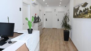 A reception area with a desk, computer, and potted plants. - EMAR Beachfront Hotel Ksamil (Ksamil)