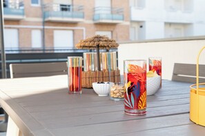 Una mesa con varios recipientes de vidrio, un cuenco pequeño de nueces y un paraguas decorativo de paja.