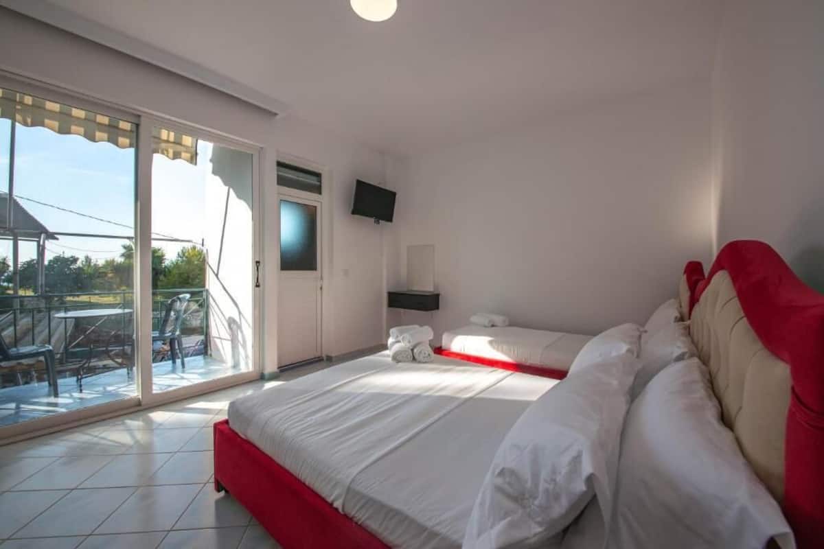 Une chambre dotée d’un grand lit, d’une télévision et d’un balcon aménagé avec du mobilier d’extérieur.
