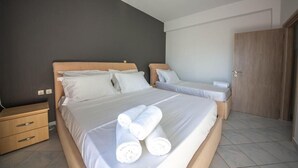Un dormitori amb dos llits, una tauleta de nit de fusta i una porta.