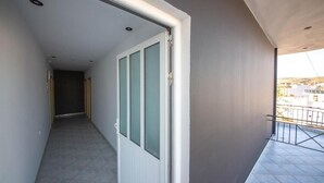 Passadís estret amb una porta corredissa de vidre que dona a un balcó amb barana metàl·lica.