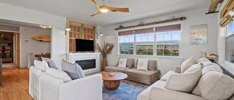 A modern living room with a fireplace, a television, and a large window with a view of the outdoors.