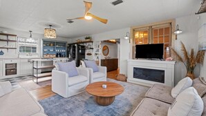 A modern living room with a fireplace, white sofas, a coffee table, and a TV.