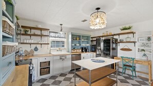A kitchen with a checkered floor, wooden cabinets, a white countertop, and a hanging light fixture.