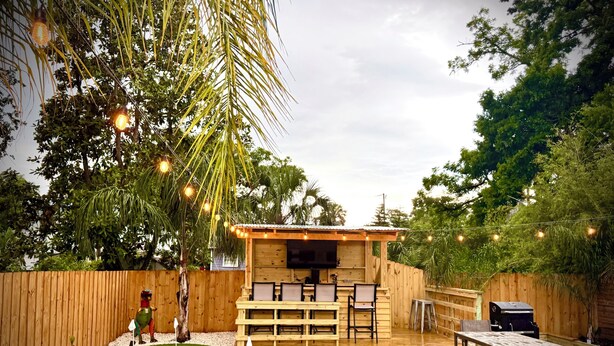 A wooden deck with a barbecue area, a small pool table, and a seating area with a TV. - Completely renovated luxury home. Putt putt golf, bocce, etc.  Walk to downtown! (St. Augustine)