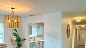 A spacious kitchen with modern appliances, a dining area with a wooden table and chairs, and a hallway leading to other rooms. - Completely renovated luxury home. Putt putt golf, bocce, etc.  Walk to downtown! (St. Augustine)