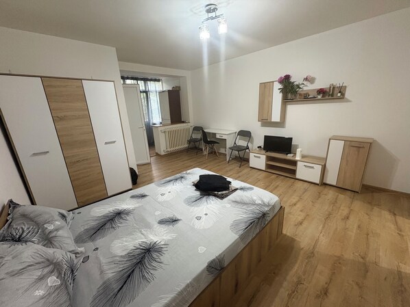 A bedroom with a bed, a desk, a chair, a TV, and a wardrobe.