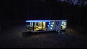 En modern, upplyst tågvagn med en glasfront, en säng och en liten sittgrupp.