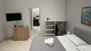 A modern hotel room with a bed, a TV, a wardrobe, and a bathroom visible through an open door. - Apartment in the heart of Naples Corso Umberto I Kitchen Wi-Fi climate center port (Napoli)
