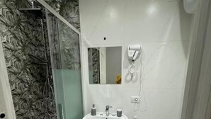 A bathroom with a glass shower enclosure, a pedestal sink, a toilet, and a hairdryer mounted on the wall. - Apartment in the heart of Naples Corso Umberto I Kitchen Wi-Fi climate center port (Napoli)