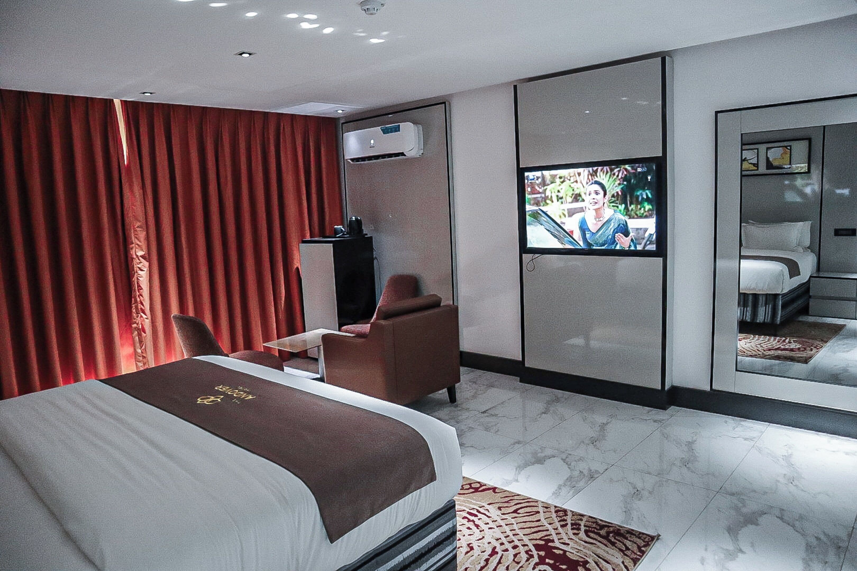 Een moderne hotelkamer met een groot bed, een televisie, een bureau en een zithoek.