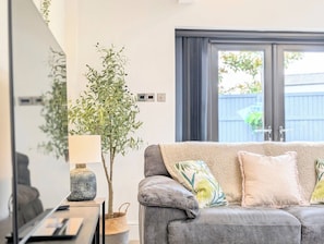 A modern living room with a grey sofa, a lamp, and a potted plant. - Birkdale Links Lodge (Southport)