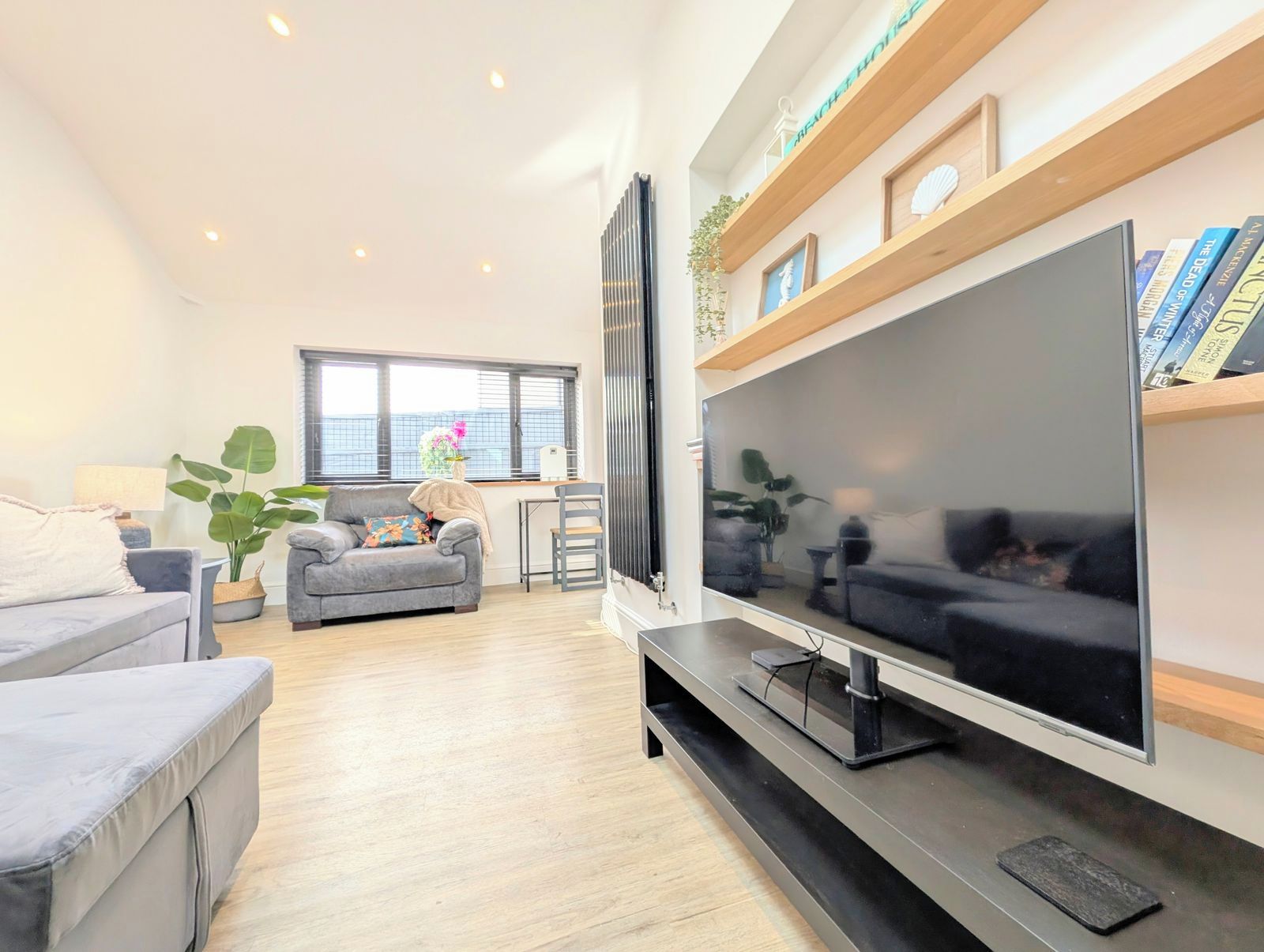 A modern living room with a large flat-screen TV, a sofa, a coffee table, and a dining area with a table and chairs.