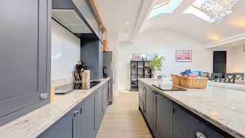 A modern kitchen with dark cabinetry, a marble countertop, and a central island.