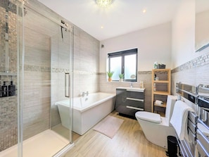 Une salle de bain moderne dotée d’une douche à parois de verre, d’une baignoire sur pieds, d’un meuble-lavabo et de toilettes.