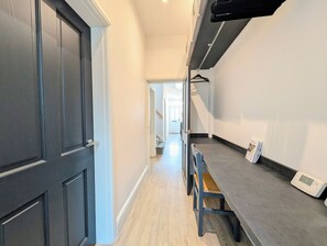 A hallway with a dark door, a light-colored wall, and a grey countertop with a digital thermostat. - Birkdale Links Lodge (Southport)