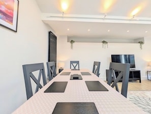 A conference room with a long table, chairs, a television, and a plant.