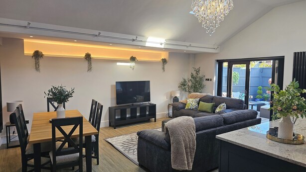 A modern living room with a dining area, a large TV, and a cozy sofa.