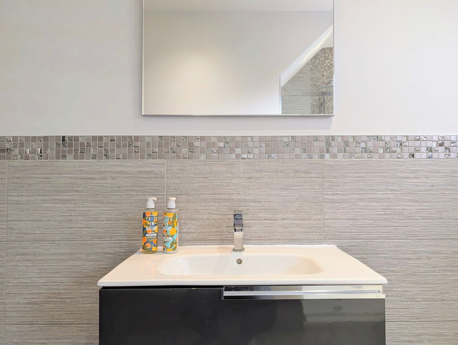 Un bagno con un lavandino, due flaconi di sapone per le mani e uno specchio sopra il lavandino.