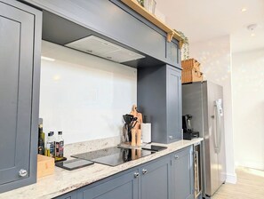 Una cocina moderna con armarios grises, un refrigerador de acero inoxidable y un horno empotrado.