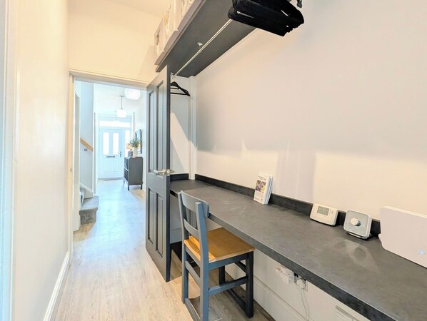 Un pasillo estrecho con una zona de cocina a la derecha, que incluye una encimera, una silla y una pequeña mesa.