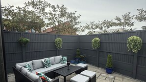 A patio with a sofa set, a table, and potted plants.