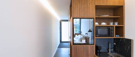 A modern kitchen with wooden cabinetry, a microwave, and a coffee machine.