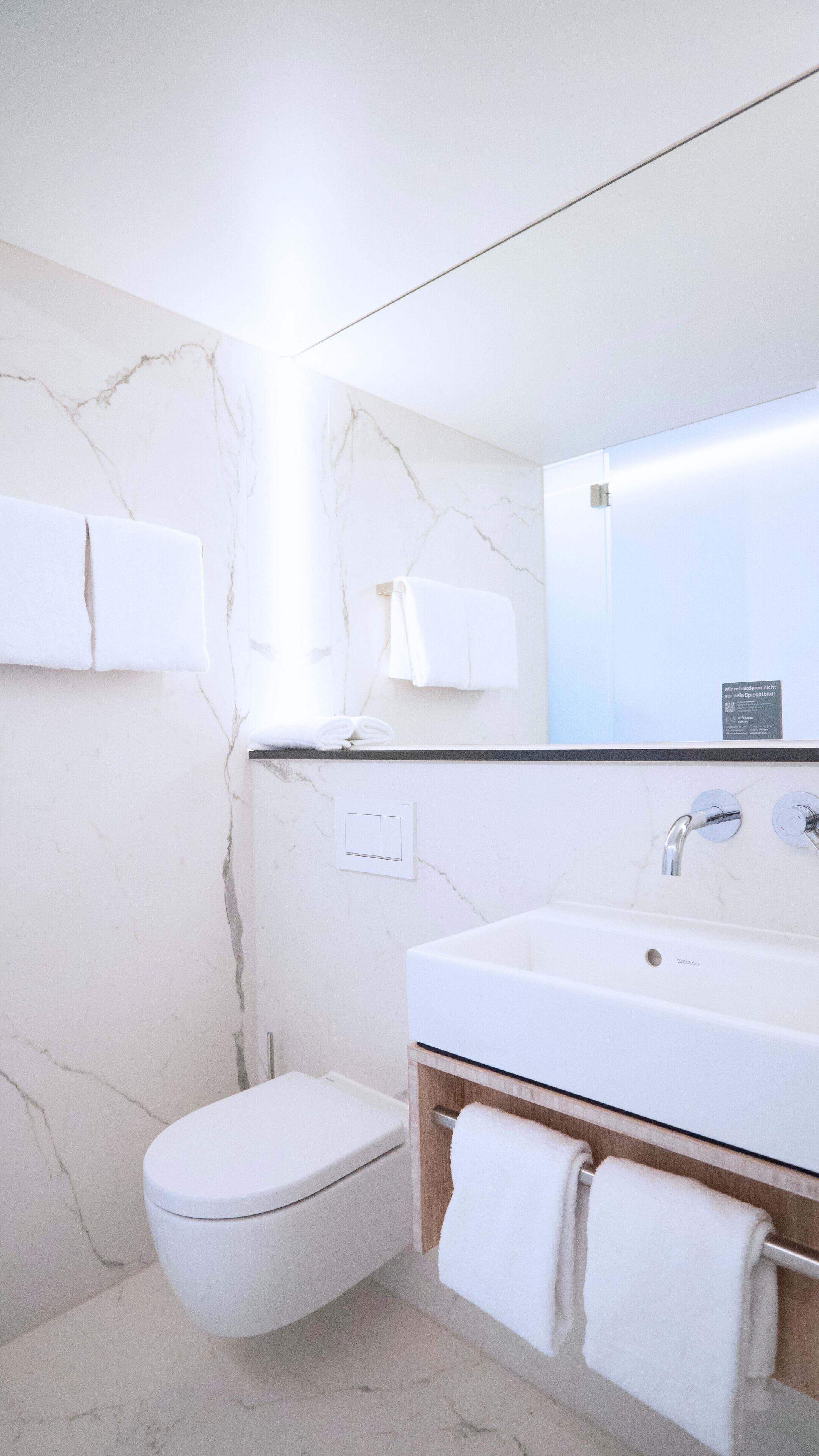 Un baño moderno con inodoro, lavamanos y espejo.