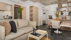 A modern living space with a sofa, coffee table, and dining area. - Central Sea Point Studio | Rooftop Pool (Cape Town)