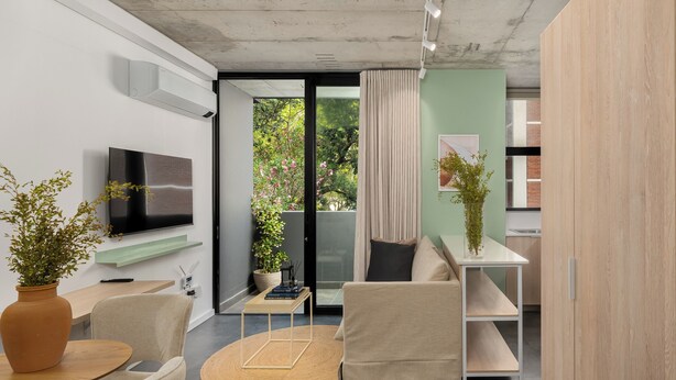 A modern living room with a sofa, a TV, a coffee table, and a dining area with a table and chairs. - Central Sea Point Studio | Rooftop Pool (Cape Town)