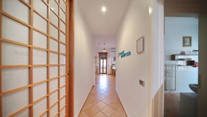A hallway with a tiled floor, a wooden door with a grid pattern, and a sign on the wall.