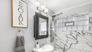 Une salle de bain avec un mur en marbre, un lavabo, un miroir et un porte-serviettes.