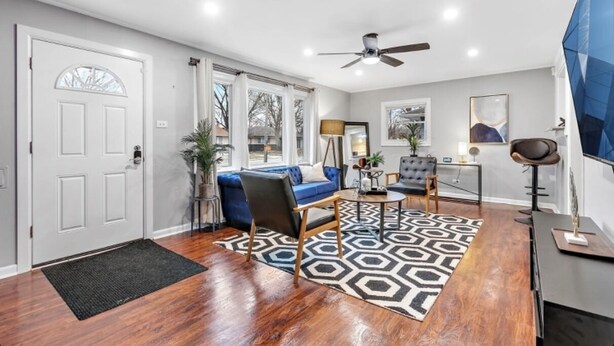 Un salon moderne avec un canapé bleu, une table basse et un ventilateur de plafond.