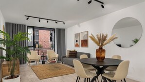Ein modernes Wohnzimmer mit Essbereich, einem großen Spiegel und Blick auf ein Backsteingebäude.