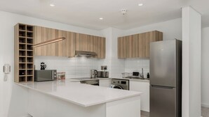Eine moderne Küche mit weißen Schränken, einem Edelstahlkühlschrank und einem eingebauten Ofen.