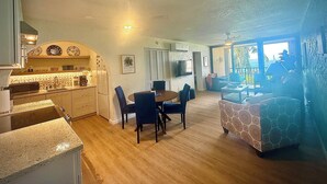 Un amplio salón con mesa de comedor, sillas, sofá y área de cocina con estufa y armarios.