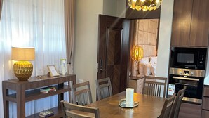 A modern dining area with a wooden table, chairs, and a chandelier. - Penthouse, (Kampala)