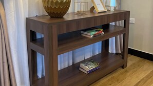 A wooden console table with a lamp, framed picture, and books. - Penthouse, (Kampala)