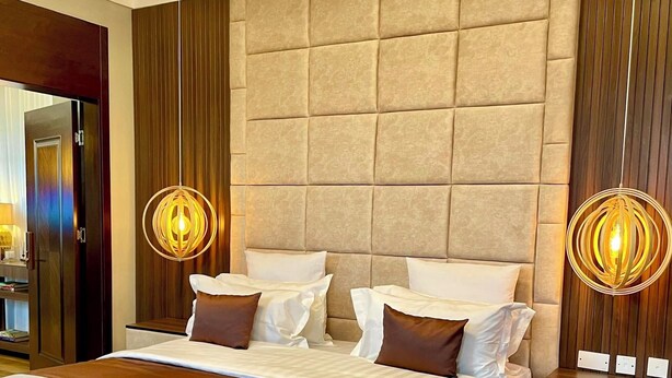 A modern bedroom with a large bed, a nightstand, and a wall-mounted light fixture. - Penthouse, (Kampala)