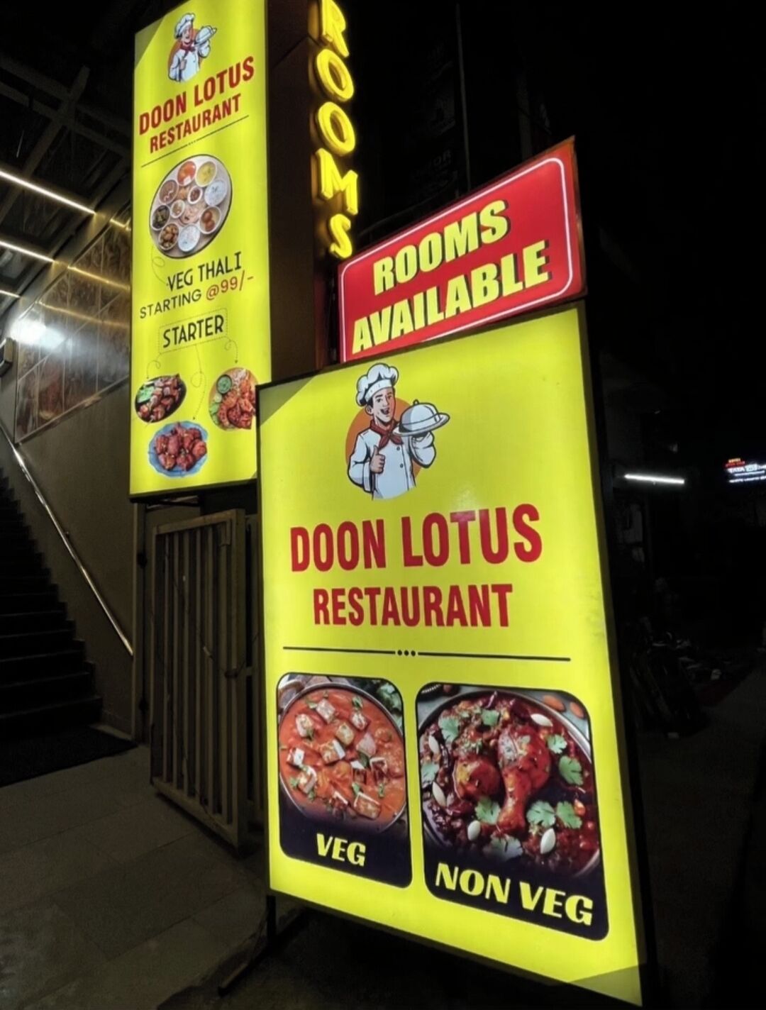 Segnaletica per il ristorante Doon Lotus che pubblicizza camere disponibili e offre opzioni vegetariane e non vegetariane.