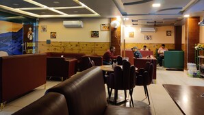 A restaurant interior with booths, tables, and a counter. - Hotel Doon Lotus (Dehradun)