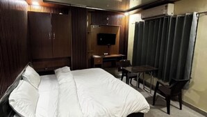 A bedroom with a large bed, a desk, a chair, a TV, and a window with curtains. - Hotel Doon Lotus (Dehradun)