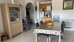 A dining area with a table, chairs, a fruit bowl, and a kitchen in the background. - 20 mns from beaches and center of St Raphaël.2 50m2 type with nice terrace. (Saint-Raphaël)