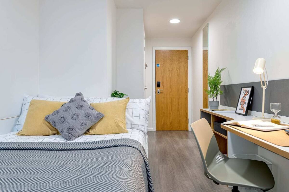 Une chambre d’hôtel moderne équipée d’un lit, d’un bureau, d’une chaise et d’une porte.