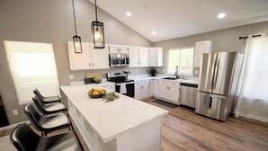 Cocina moderna con armarios blancos, electrodomésticos de acero inoxidable y una isla de mármol.