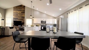 Una cocina moderna con armarios blancos, una isla grande y sillas negras.