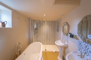 A bathroom with a bathtub, a sink, and a shower area.